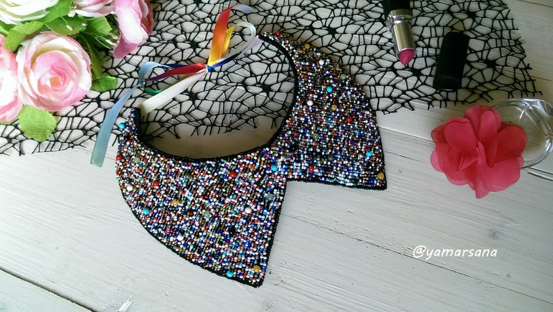 Peut inclure: Un collier de perles color&eacute; avec un dos noir. Le collier est en forme de col traditionnel avec des pointes &agrave; l'avant et &agrave; l'arri&egrave;re.