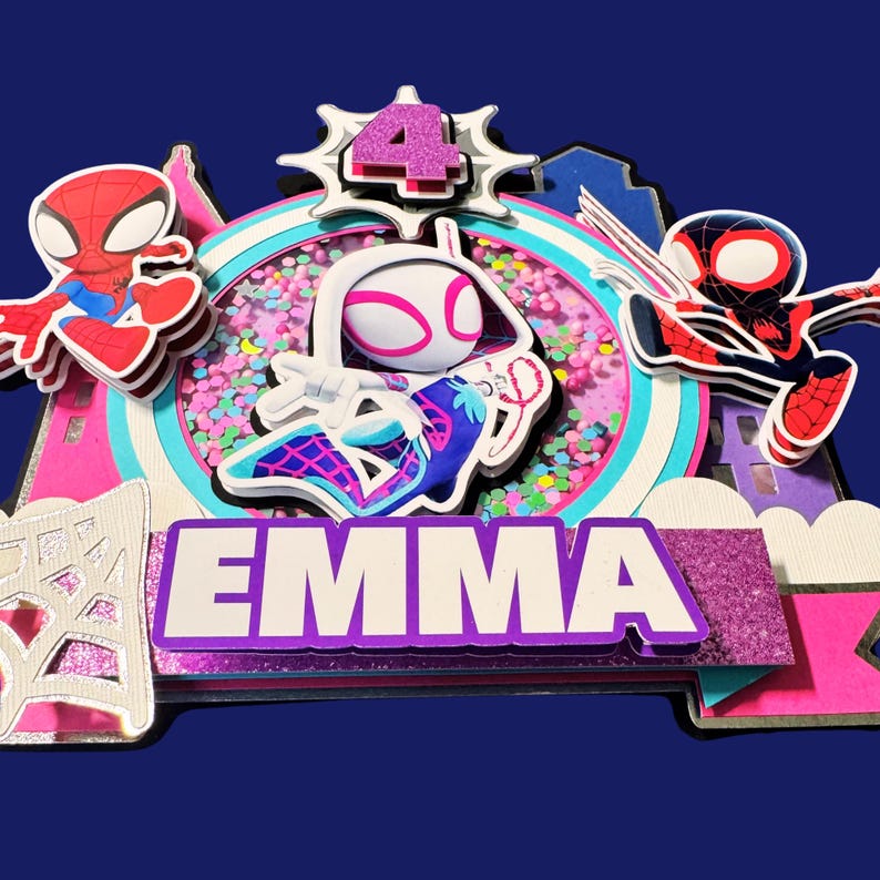 May include: A multi-layered cake topper featuring Spider-Man characters and the name "EMMA". The design includes a pink and white color scheme, a number "4", and a glittery purple banner. The background is a dark blue.
