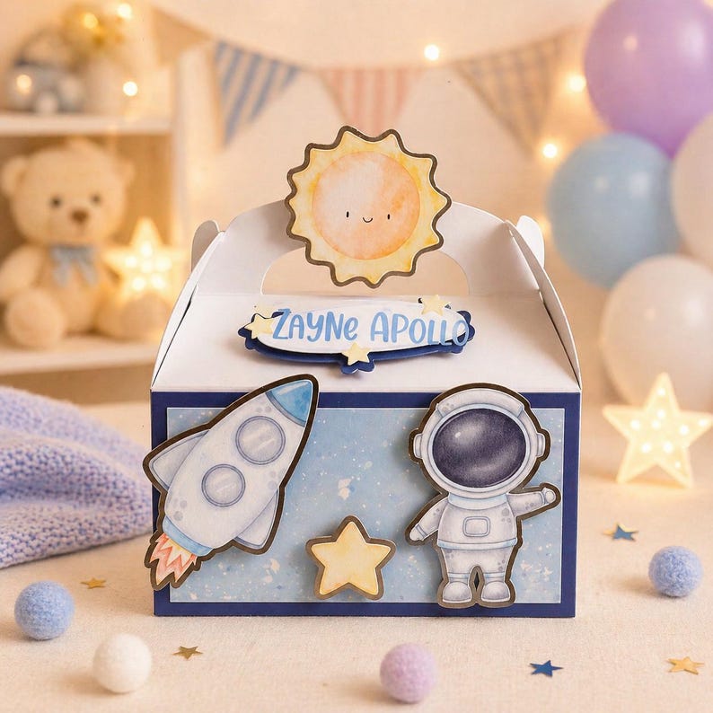 May include: A white gable box with a blue and white space theme. The box features a smiling sun, a rocket, an astronaut, and a star. The name "Zayne Apollo" is written on the box. The box is decorated with blue and purple balloons.