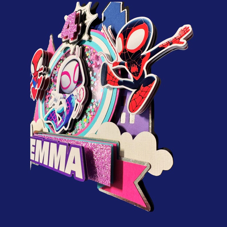 May include: A multi-layered cake topper featuring Spider-Man and Spider-Gwen characters. The design includes a rainbow, cityscape, and the name "EMMA" in white letters. The number "4" is highlighted with glitter.