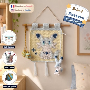 May include: A crochet wall hanging featuring a light yellow square panel with a central creature design in blue and white, suspended from a wooden dowel. The set includes a small plush creature, two decorative spheres, and text reading 3-in-1 Pattern.