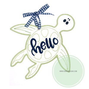 以下が含まれることがあります： 青いリボンと「hello」という文字が刺繍された緑色の亀の刺繍