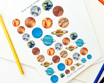 May include: A sheet of colorful planet stickers with the text "Solar System Stickers" and "Pear Tea Paperie" on it.