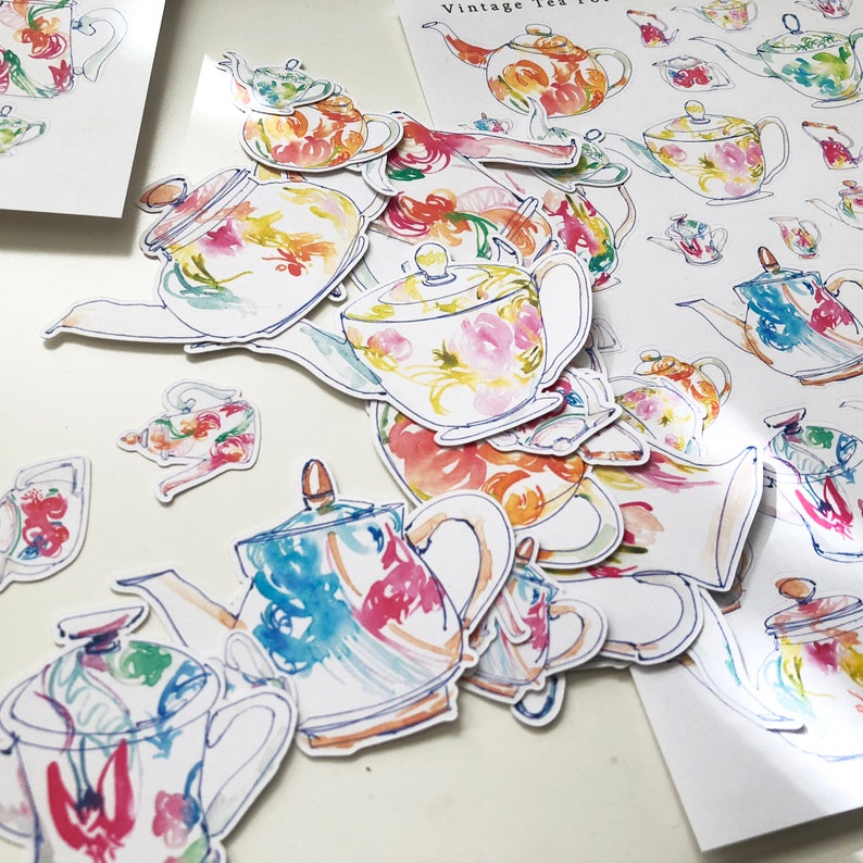 May include: A collection of vintage teapots with watercolor floral designs. The teapots are in various shades of blue, pink, yellow, and green. The teapots are on a white surface with the text "Vintage Tea" in the background.