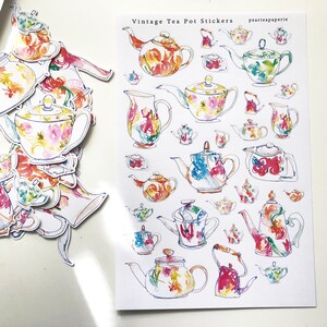 May include: A sheet of vintage tea pot stickers with watercolor illustrations of teapots in various colors and patterns. The stickers are on a white background and have the text "Vintage Tea Pot Stickers" and "peartateapaperie" printed on them.