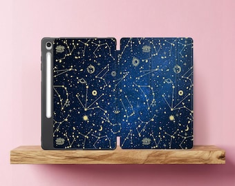 May include: A dark blue tablet case with a celestial design featuring constellations, stars, and planets in gold. The case is open, revealing the interior design. A white stylus is attached to the side of the tablet.