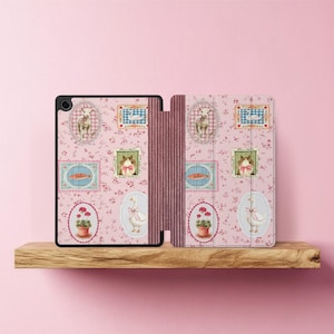 Op de afbeelding: Een roze tablet hoesje met bloemenpatroon en een decoratief ontwerp. De hoes heeft verschillende illustraties, waaronder een lam, een konijn, een gans en een wortel. De hoes is open en onthult de binnenkant.