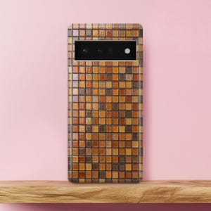 May include: A rectangular smartphone case featuring a grid pattern of small square tiles in various shades of brown, tan, and amber. The case has a horizontal black camera bar cutout near the top, revealing multiple circular camera lenses.