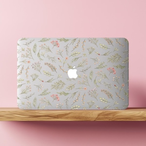 May include: A laptop case with a floral pattern. The case is light gray and covered in a repeating pattern of green leaves, small pink flowers, and sprigs. The Apple logo is visible in the center.