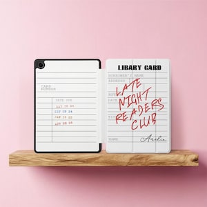 以下が含まれることがあります： 赤色の「Late Night Readers Club」という文字が入った白い図書館カードと、線が入った内側の白黒ケース。 カードには名前のスペースがあり、ケースにはカード番号と期日があります。