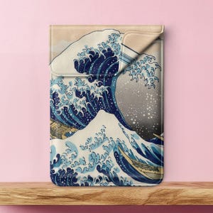 May include: A laptop sleeve with a blue and white wave design. The wave is a traditional Japanese art piece, known as "The Great Wave off Kanagawa".
