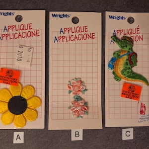 Puede incluir: Tres parches termoadhesivos en cartulina blanca con un patrón de cuadrícula. Los parches están a la venta y presentan un girasol amarillo, dos flores rosas y un cocodrilo verde con una mochila azul. Las tarjetas tienen el texto "Applique Applicacione" e "Inventory Reduction Sale!" impreso en ellas.