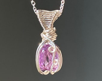 May include: A silver chain necklace with a purple gemstone pendant. The pendant is wrapped in silver wire.