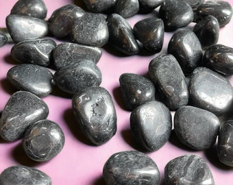 May include: A collection of smooth, black tumbled stones. The stones are various sizes and shapes, and have a glossy finish.
