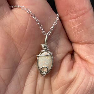 May include: A silver chain necklace with a white opal pendant wrapped in silver wire.