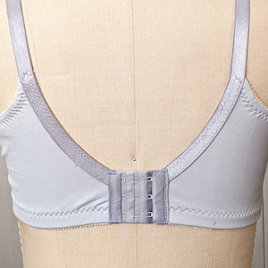 Może przedstawiać: Jasny szary biustonosz z regulowanymi ramiączkami i zapięciem na haftki z tyłu.