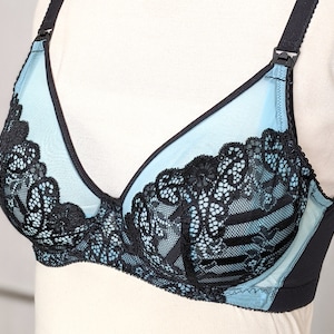 Może przedstawiać: Jasno błękitna i czarna koronkowa biustonosz z regulowanymi ramiączkami. Biustonosz ma delikatny kwiatowy wz&oacute;r i gładkie, jedwabiste wykończenie.