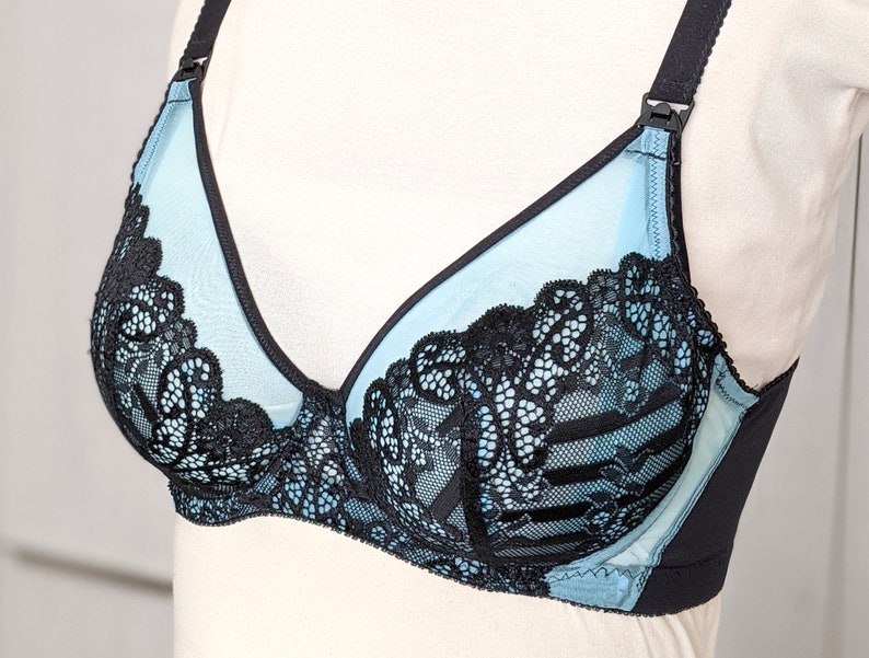 Może przedstawiać: Jasno błękitna i czarna koronkowa biustonosz z regulowanymi ramiączkami. Biustonosz ma delikatny kwiatowy wz&oacute;r i gładkie, jedwabiste wykończenie.