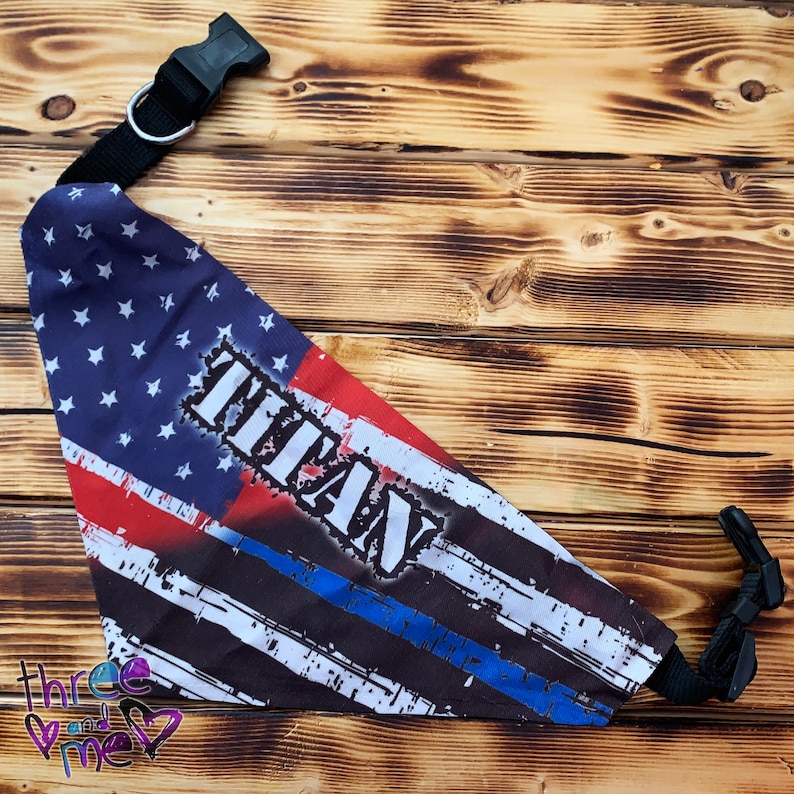 May include: A blue, red, and white bandana with a thin blue line and the word "TITAN" printed on it. The bandana is attached to a black adjustable collar.