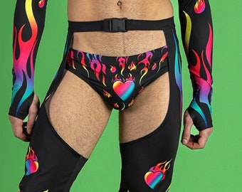 Può includere: Una persona indossa un top corto nero con fiamme e cuori arcobaleno, pantaloni neri con fiamme e cuori arcobaleno e scarpe platform nere.
