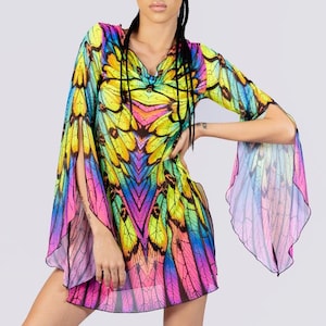 May include: A vibrant, short dress with a butterfly wing pattern in shades of yellow, pink, blue, and purple. The dress features long, flowing sleeves and is paired with black platform boots. The overall style is bold and eye-catching.