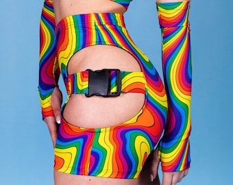 May include: A vibrant rainbow-colored outfit featuring a crop top, high-waisted shorts with a cut-out design, and arm sleeves. The outfit has a wavy pattern in shades of red, orange, yellow, green, blue, and purple. The shorts have a black buckle.