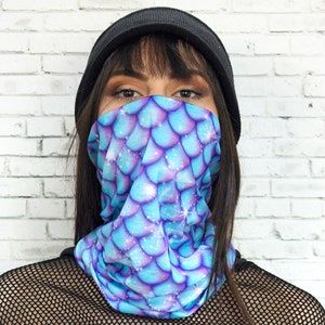 May include: A black beanie with a blue and purple mermaid scale patterned face mask. The mask is worn by a person with black hair and is covering their mouth and nose.