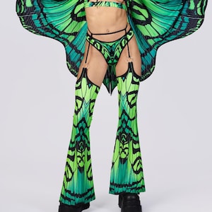 May include: A vibrant green and black butterfly-themed outfit. The ensemble includes a crop top, high-waisted bottoms with garter straps, flared pants, and a cape. The outfit is made of a pleated fabric with a butterfly wing design.