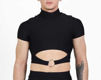 May include: A black mock neck shirt with a cut-out detail and a silver ring at the waist. The shirt is paired with black trousers with a zip and silver rings on the legs.