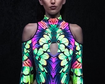 Puede incluir: Un body negro con un estampado de mariposa colorido. El body tiene cuello alto, mangas largas y un escote de ojo de cerradura en el pecho. Las mangas son acampanadas y tienen una superposición transparente.