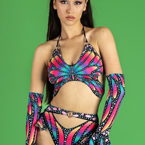 May include: A black halter top and matching shorts with a rainbow butterfly print. The top has a cut-out design and the shorts have a high waist and a cut-out detail on the front. The outfit is accented with a silver heart-shaped ring.