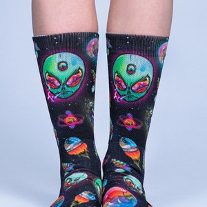 May include: A pair of black socks with a colorful, psychedelic print of aliens, planets, and stars. The socks are made of a soft, comfortable material and are perfect for adding a touch of fun to any outfit.