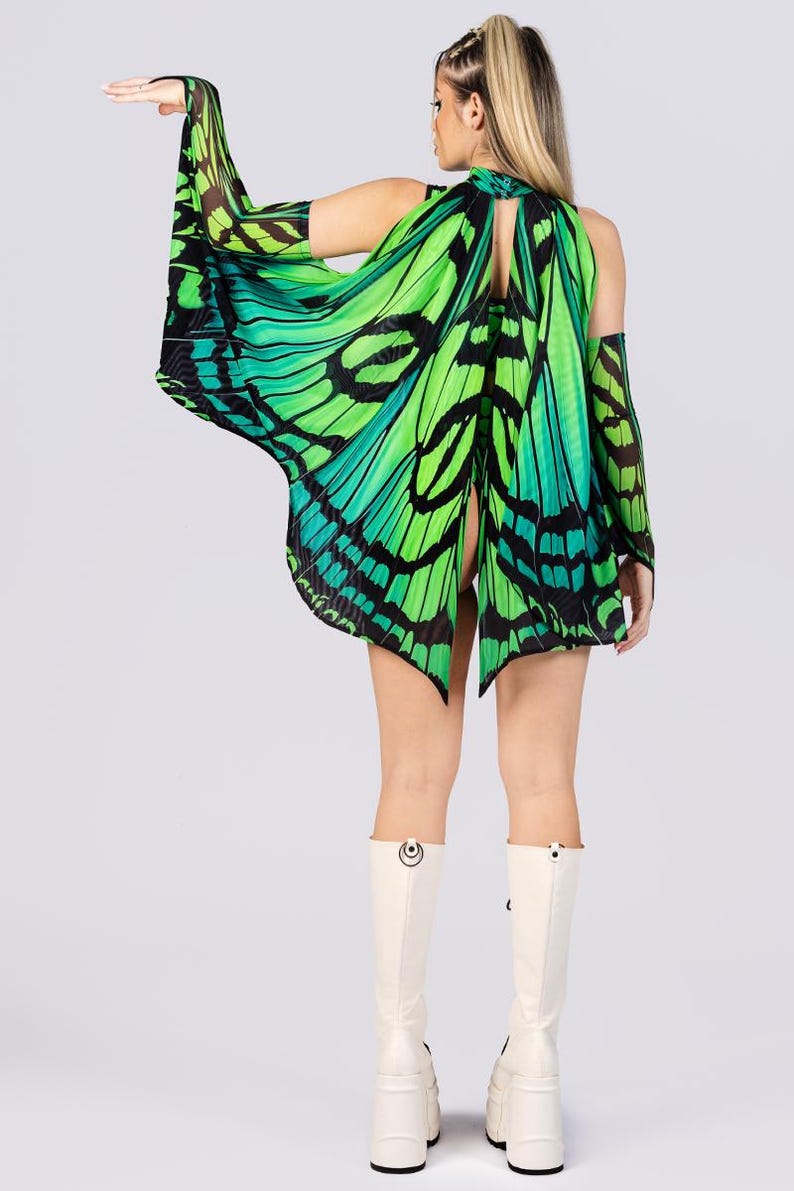 May include: A green and black butterfly wing costume with matching arm sleeves. The costume is worn with white platform boots. The butterfly wings are a vibrant green with black detailing, creating a striking visual effect. The outfit is designed to resemble butterfly wings.