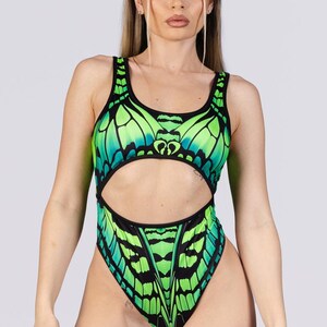 May include: A one-piece swimsuit with a butterfly wing design in shades of green and black. The swimsuit has a cutout at the waist and a high-cut leg. The butterfly wing pattern is detailed and vibrant.