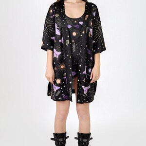 May include: A black kimono with a celestial print featuring butterflies, stars, and moons. The kimono has a short sleeve and is made of a silky fabric.