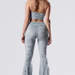 Op de afbeelding: Een lichtblauwe twee-delige outfit met een tube top en een broek met wijde pijpen. De stof heeft een subtiele distressed look.