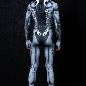 May include: A full-body suit with a silver and black design featuring intricate patterns. The suit is form-fitting and has a high neck.