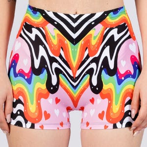 May include: Shorts with a vibrant, colorful design. The shorts feature a pink base with small white and red hearts. A rainbow pattern with black and white wavy lines is the main design element. The shorts are made of a stretchy material.