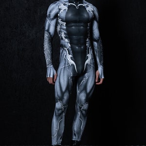 May include: A black and white bodysuit with a detailed anatomical design. The bodysuit has a zip at the front and long sleeves. The model is wearing black boots.