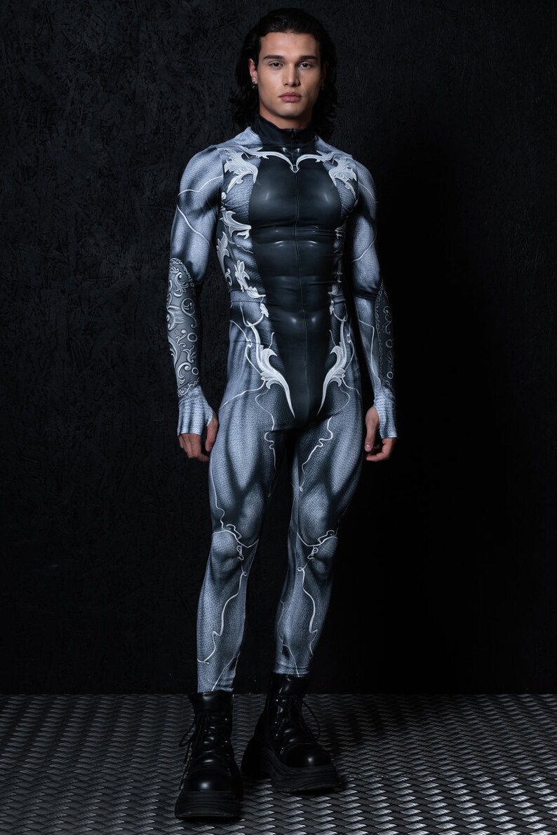 May include: A black and white bodysuit with a detailed anatomical design. The bodysuit has a zip at the front and long sleeves. The model is wearing black boots.