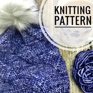 May include: Blue knitted hat with a white pom pom and a brown leather tag that says "Weird Sheep". The hat is on a wooden surface with a ball of blue yarn and a mug with a floral pattern.