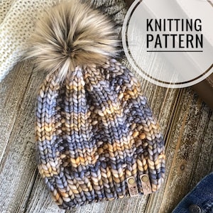 May include: A knitted beanie hat with a fluffy pom pom in shades of blue, brown, and yellow. The hat has a woven label that reads "WeDo Sheep".