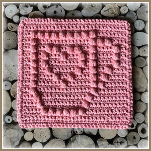 Könnte beinhalten: Ein rosa gehäkelter Geschirrtuch mit einem strukturierten Design. Das Geschirrtuch ist quadratisch und mit einem Reliefmuster gearbeitet.