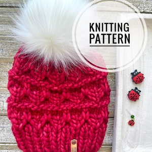 May include: A red knitted beanie with a white faux fur pom pom. The beanie has a cable knit pattern and is made with a chunky yarn. The text "Knitting Pattern" is written in a white circle on a white background.