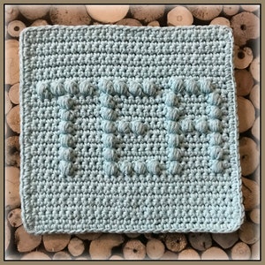 Könnte beinhalten: Ein hellblauer gehäkelter Geschirrtuch mit einem erhabenen, strukturierten Design, das das Wort "MUTTER" buchstabiert.