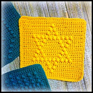 May include: A square, yellow crocheted item with a raised star pattern, on a wooden surface. Two teal crocheted items are partially visible, providing a contrast of colour and texture.