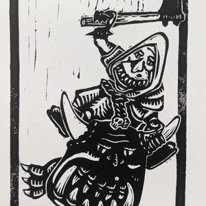 May include: Black and white linocut print depicting a hooded figure wielding an axe while riding a creature. The print is titled "Seer Squig 2024". The artwork is framed with a black border and has a textured background.