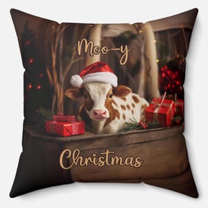 Peut inclure: Coussin carré avec une vache marron et blanche portant un bonnet de Père Noël. La vache est entourée de cadeaux rouges et de verdure. Les mots "Moo-y Christmas" sont écrits en lettres dorées.