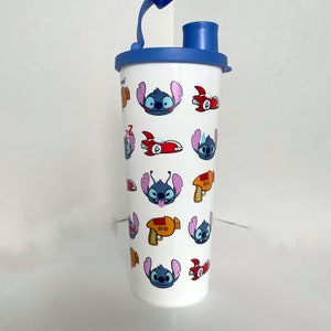 May include: A white reusable water bottle with a blue lid and a blue straw. The bottle has a repeating pattern of Stitch from Lilo & Stitch, spaceships, and laser guns.