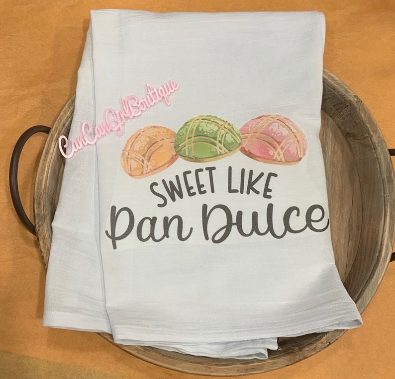 Puede incluir: Una toalla de cocina azul claro con un gr&aacute;fico de tres pasteles pan dulce y el texto "Sweet Like Pan Dulce".